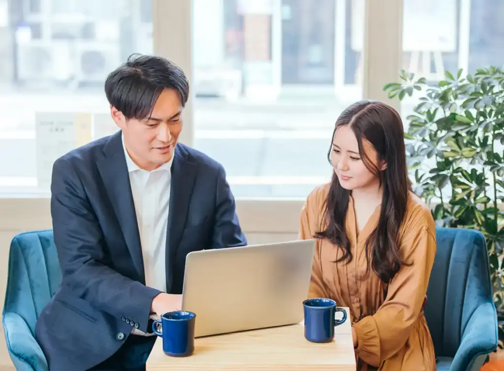 パソコンを広げて打合せをする2名の人